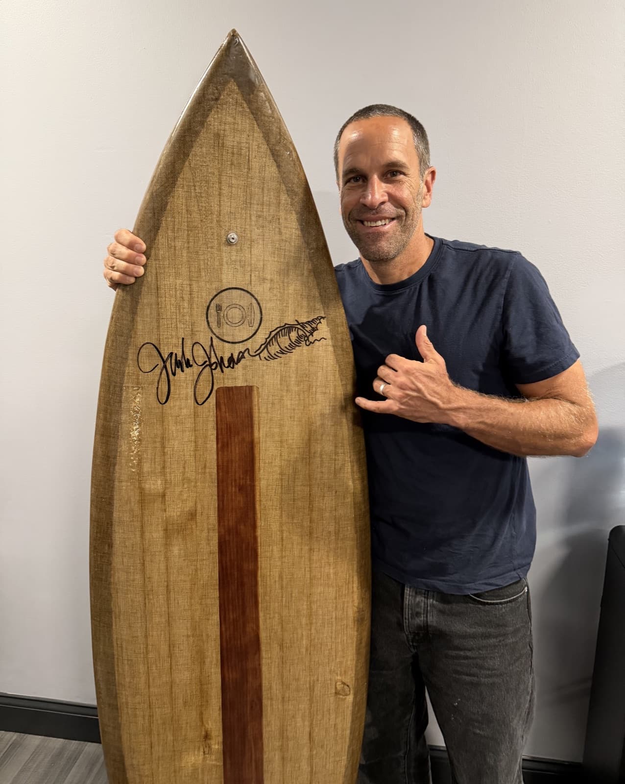 Kyle holding a signed wooden Dish surfboard